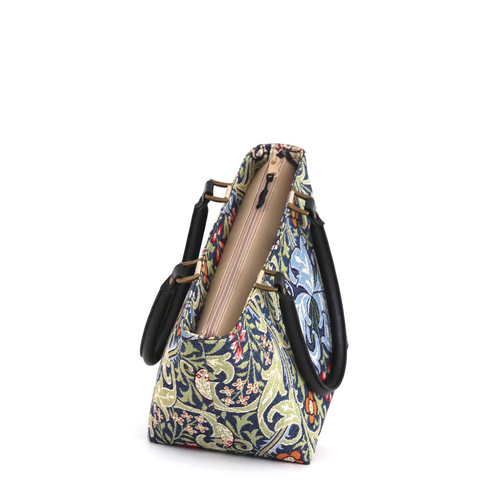 Angled view of the William Morris Golden Lily handbag showing the zip-top closure,  structured base and intricate tapestry weave in navy, sage green and coral with antique brass hardware, handmade in Great Britain by Umpie Handbags