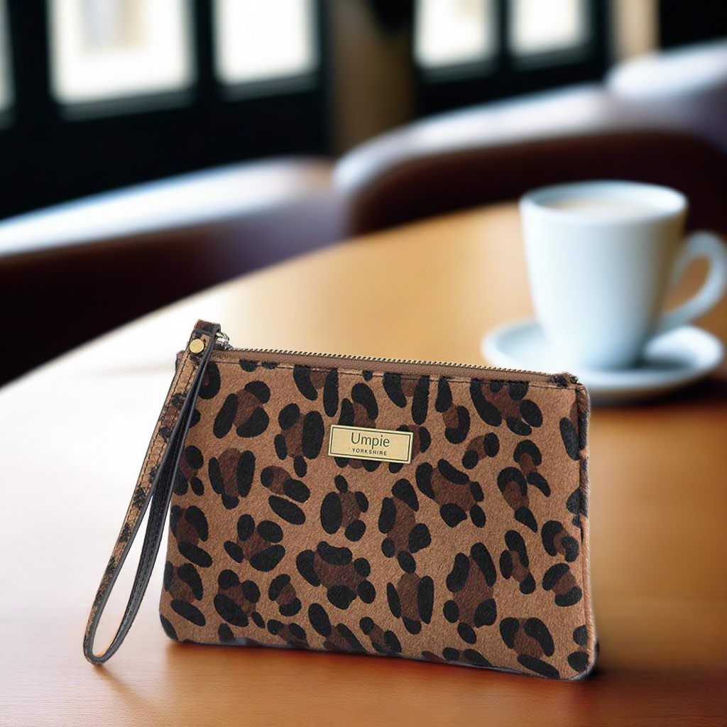 Compact leopard clutch bag with secure wrist strap detail, side angle showing sleek silhouette and quality craftsmanship of hair on leather construction by Umpie Handbags