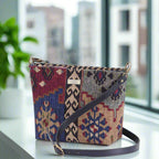 Canvas crossbody bag showcasing intricate Kilim design with traditional diamond motifs, premium black leather strap with brass buckle adjustment, compact structured silhouette - angled view by Umpie Handbags