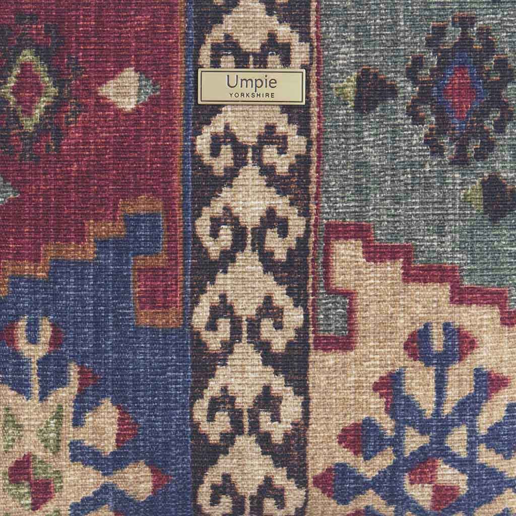 Close-up detail of luxury canvas fabric displaying authentic Kilim weaving pattern in deep burgundy, navy blue, and taupe geometric designs with visible textile texture - fabric detail by Umpie Handbags